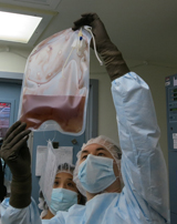 Two technicians in Penn Medicine's Clinical Cell and Vaccine Production Facility hold up a bag of modified T cells. Image: Penn Medicine